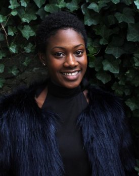 Young woman standing infront of ivy.